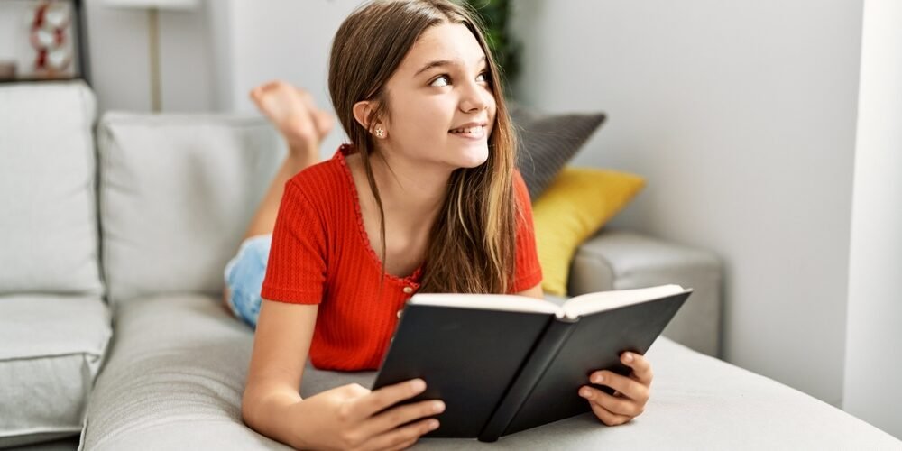 Adorable,Girl,Smiling,Confident,Reading,Book,At,Home